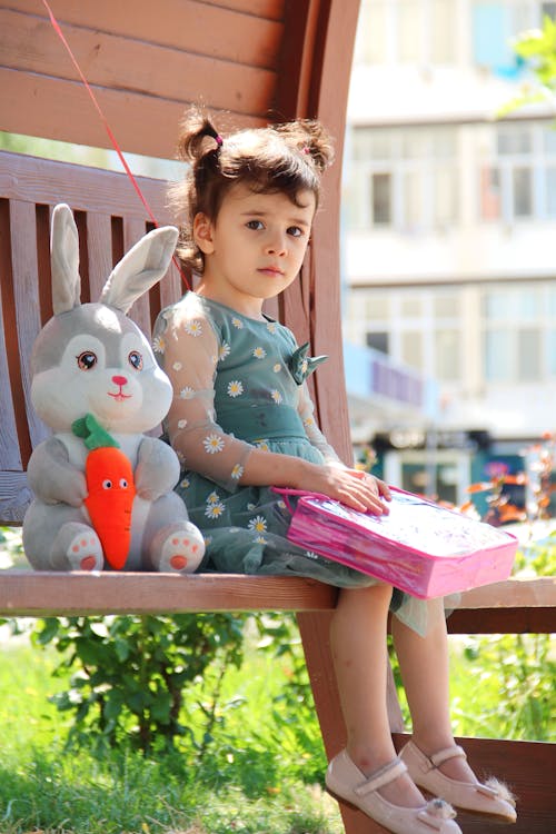 Free A Little Girl Sitting on a Bench with Her Teddy Bear  Stock Photo