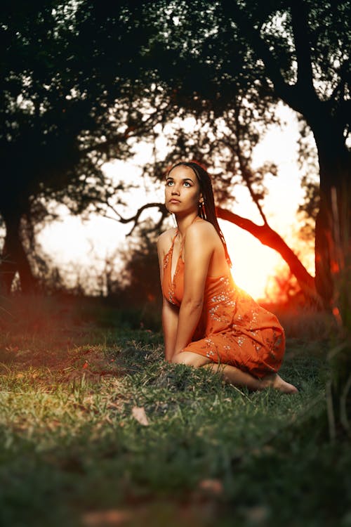 Young Woman in an Orange Dress Posing Outside at Sunset 