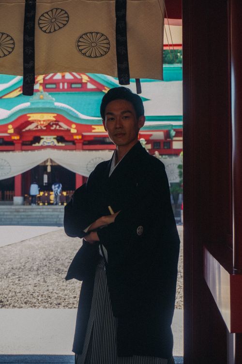 Free Japanese man in traditional attire standing at a shrine entrance, showcasing culture and heritage. Stock Photo