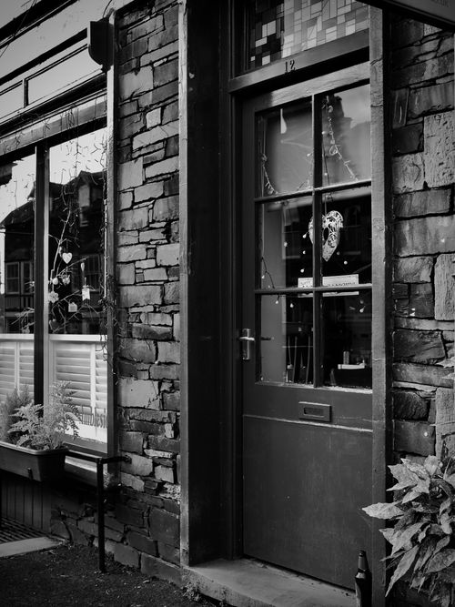 Free Stylish black and white image of a rustic stone building facade with a classic wooden door and window display. Stock Photo