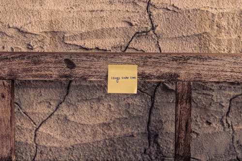 Sticky Note on Wooden Bar on Cracked Wall