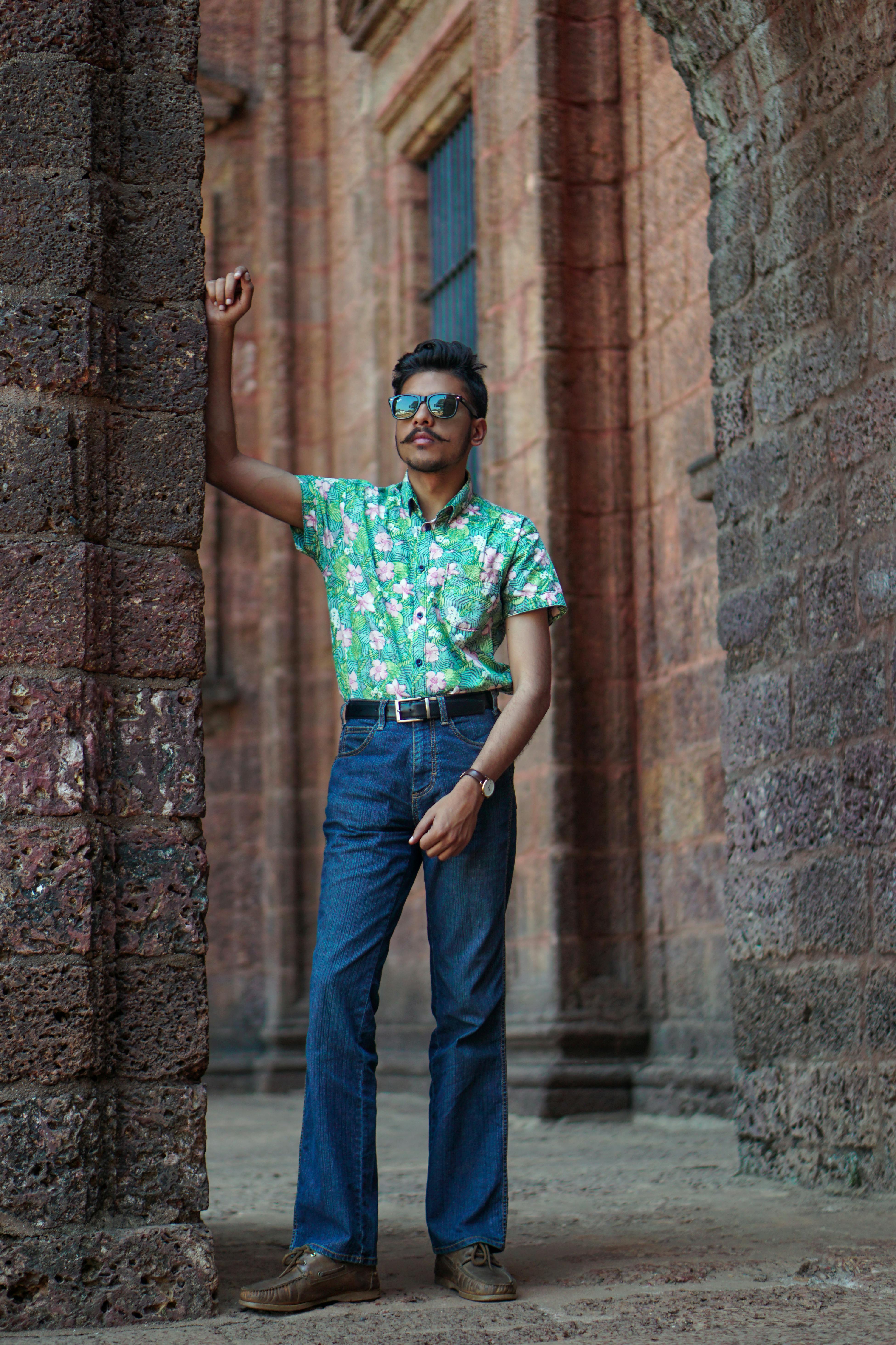 年轻人戴着墨镜，靠在砖砌拱门上摆姿势，展现城市风格