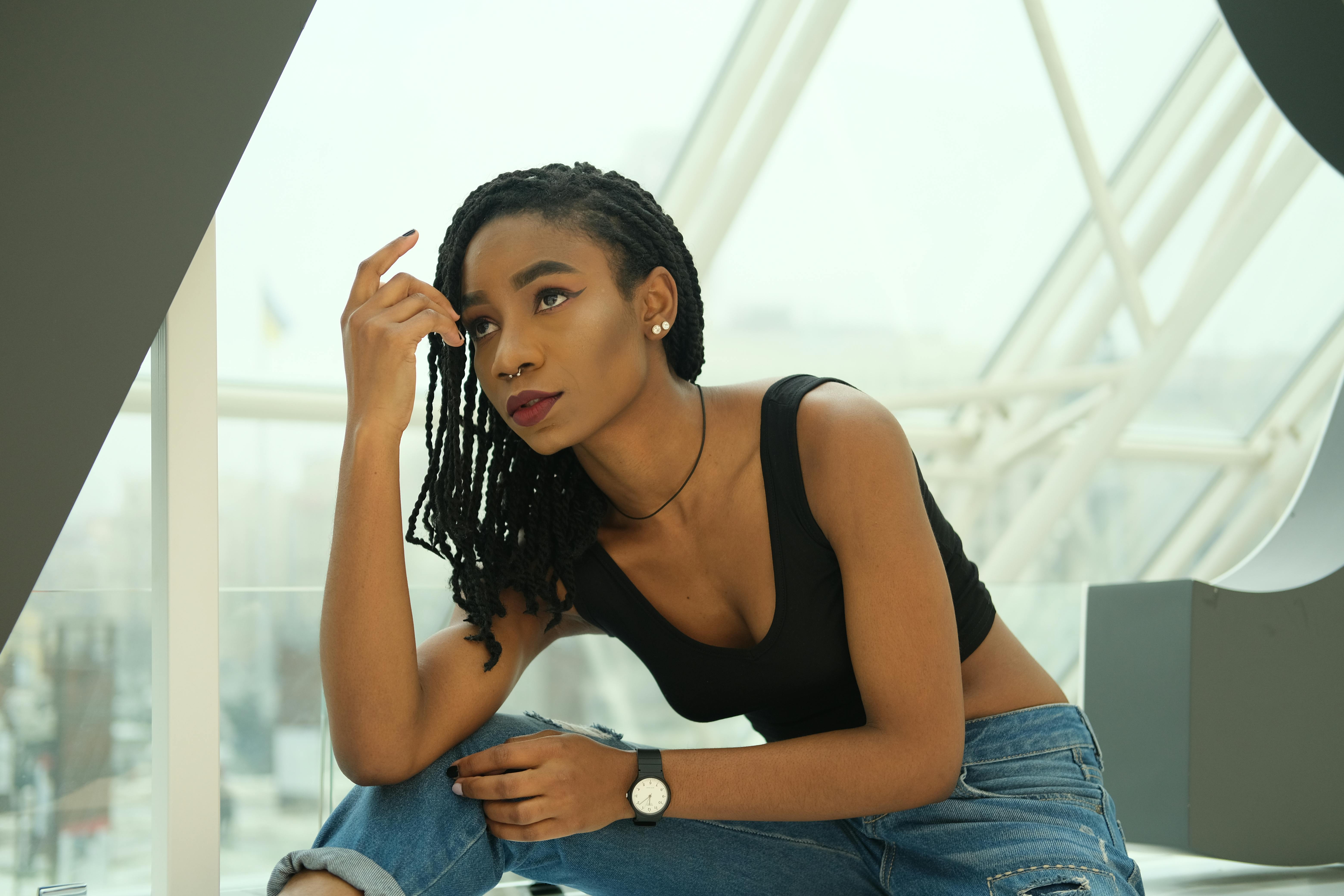 一位穿着休闲装的时尚年轻女子，在现代室内环境中若有所思地摆着姿势