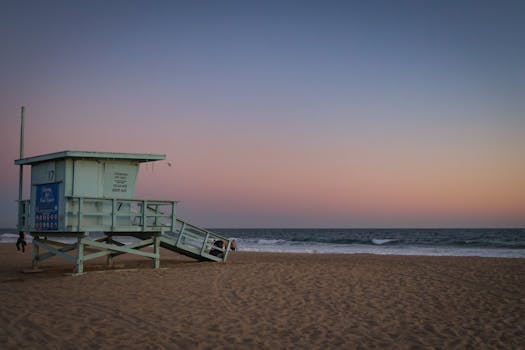 Beautiful dusk scene at Santa Monica Beach with a lifeguard tower and pastel sky, capturing the essence of a summer evening.