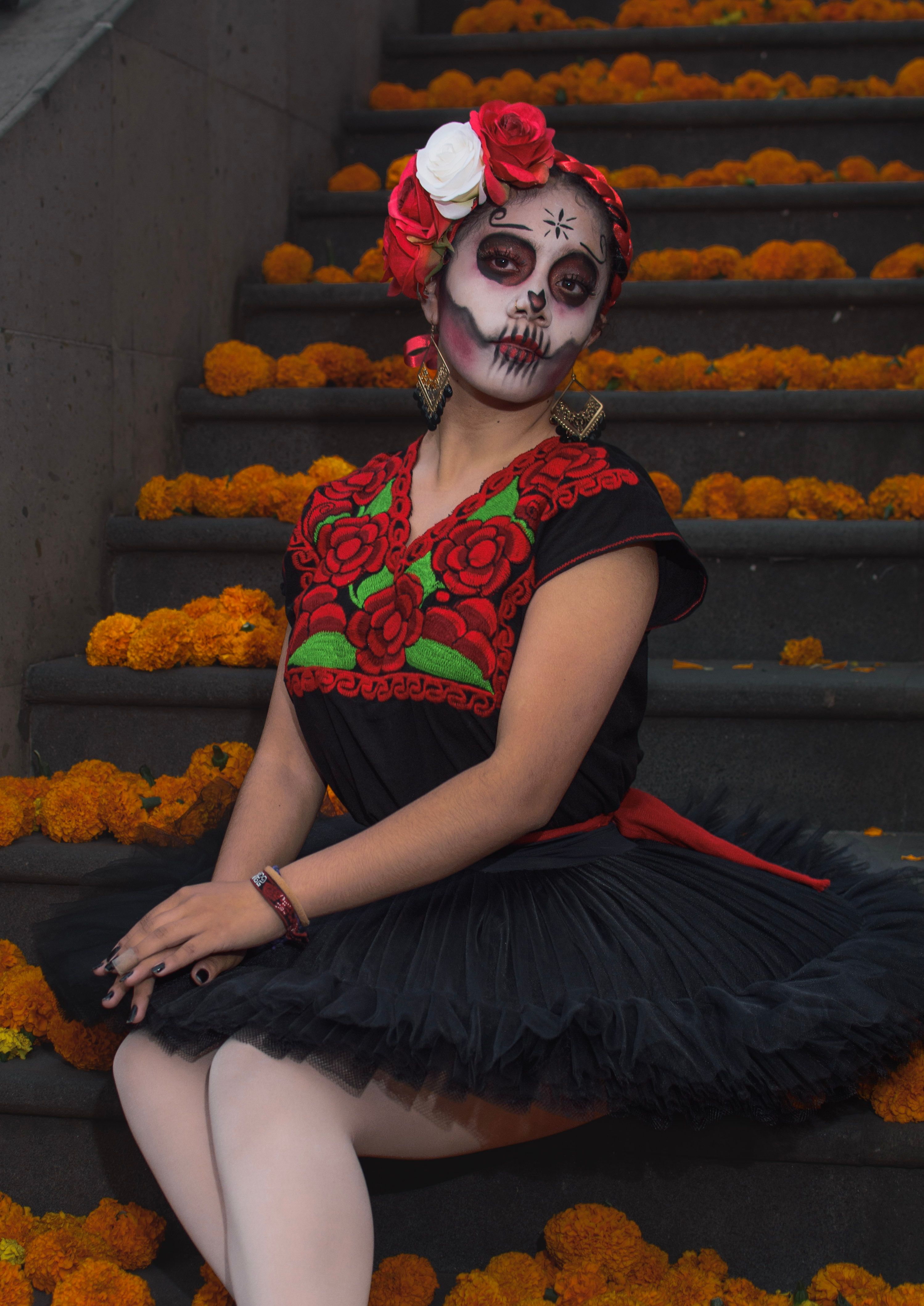 A woman dressed as a skeleton sits on some steps · Free Stock Photo
