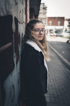 Portrait of a young woman with glasses standing on a sidewalk in Clifton, UK.