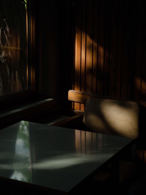 Free Peaceful seating area in soft light, highlighting shadows on wooden walls and chair. Stock Photo