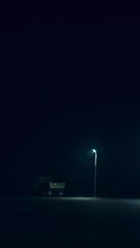 A solitary truck parked under a street lamp on a dark urban night, creating a moody atmosphere.