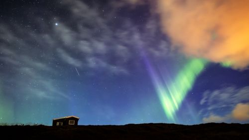 Free Beautiful aurora borealis illuminating the night sky above a solitary cabin in Iceland. Perfect for travel and nature enthusiasts. Stock Photo