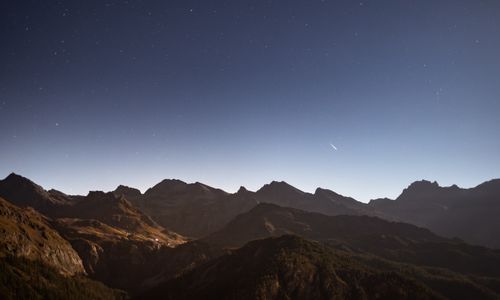 Free Breathtaking view of starry night sky over rugged Italian alpine mountains. Perfect for adventure and travel enthusiasts. Stock Photo