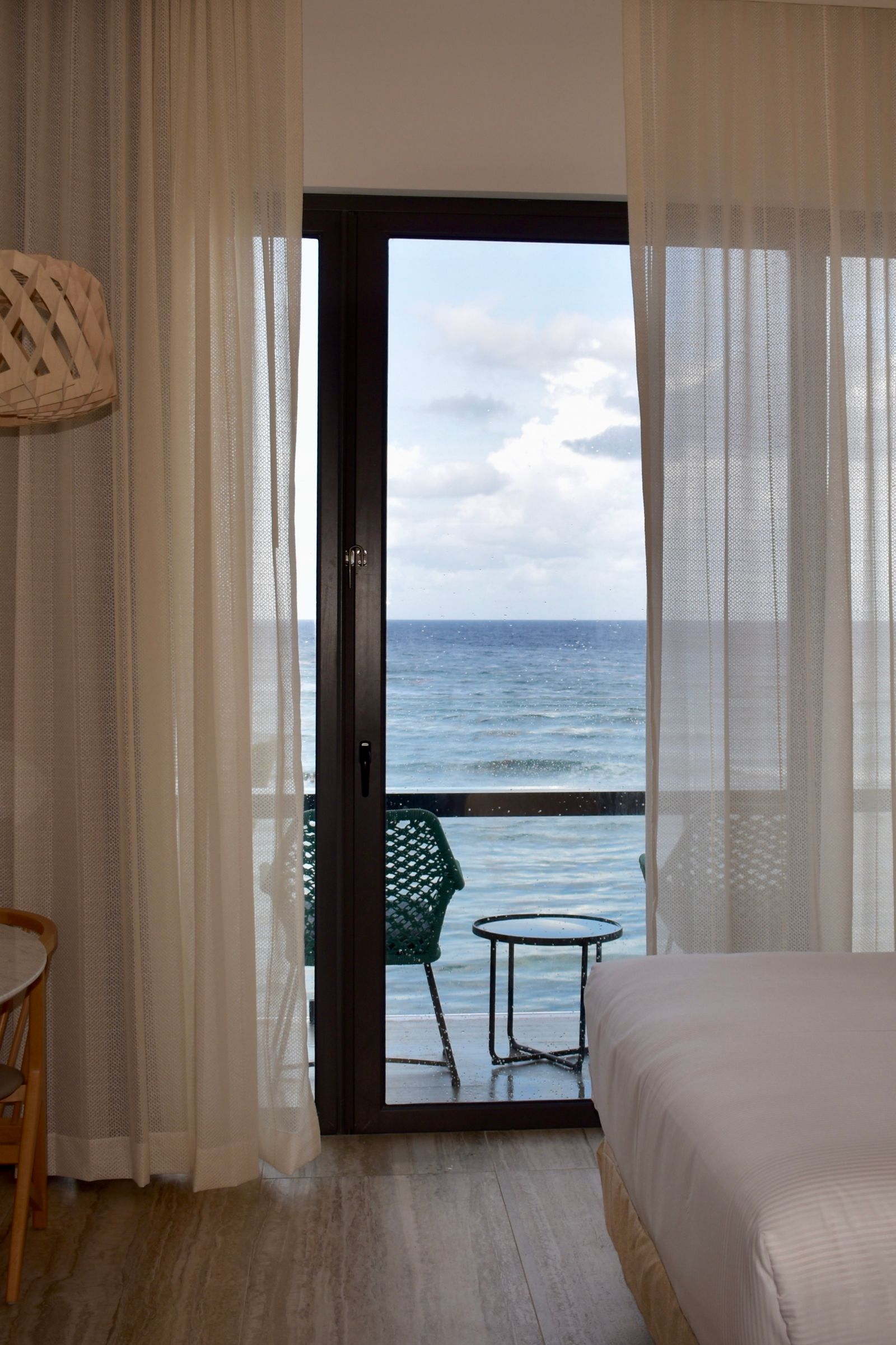 Hotel bedroom with balcony doors opening toward the water.