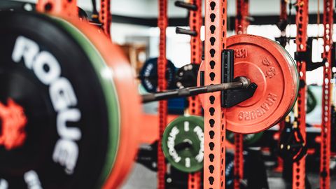 Detailed view of a weightlifting setup in a modern gym featuring colorful weight plates on a barbell.