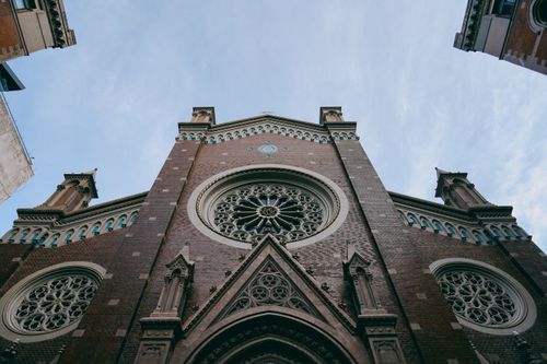 Free A detailed look at a church's ornate facade with rose windows, captured from a low angle. Stock Photo