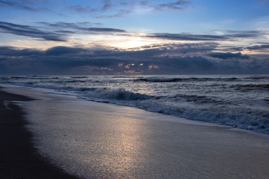 Peaceful view of waves under a moody sunset sky on Sylt beach, Germany.