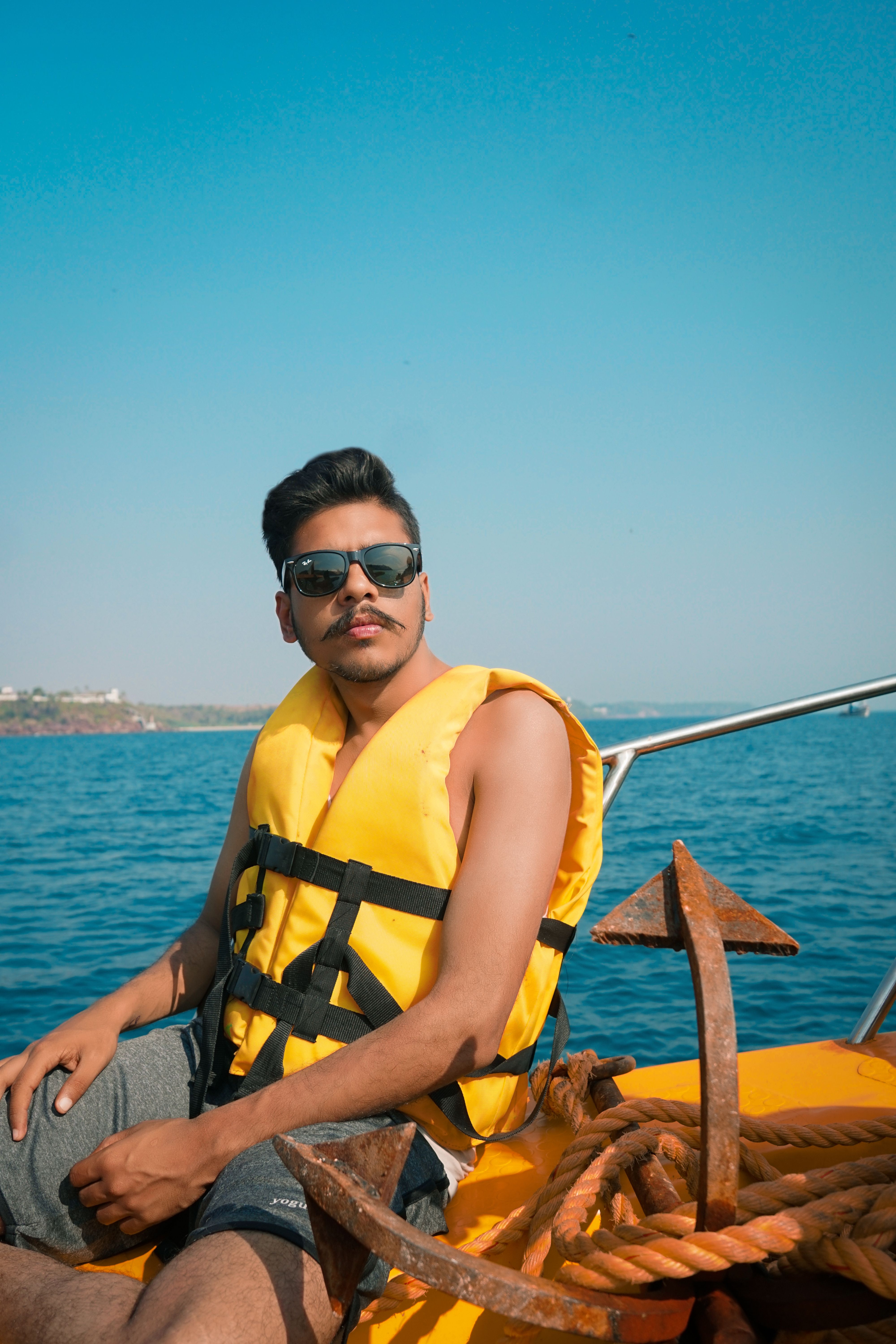 Young man in yellow life jacket and sunglasses enjoying a sunny boat trip on the ocean.