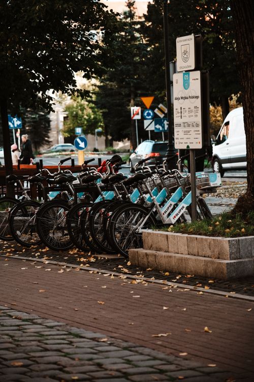 Free A row of rental bikes parked on a city sidewalk, perfect for exploring urban streets. Stock Photo