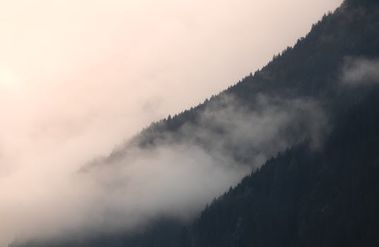 Serene misty mountain scene at sunrise with a calm, atmospheric feel.
