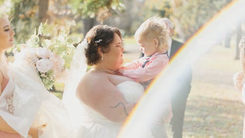 Woman in Wedding Dress Holding Child