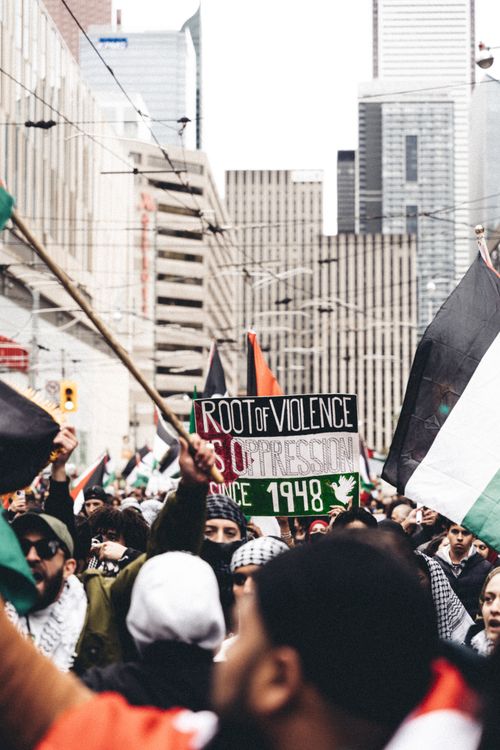 Free A vibrant street protest with flags and signs against a city backdrop. Stock Photo