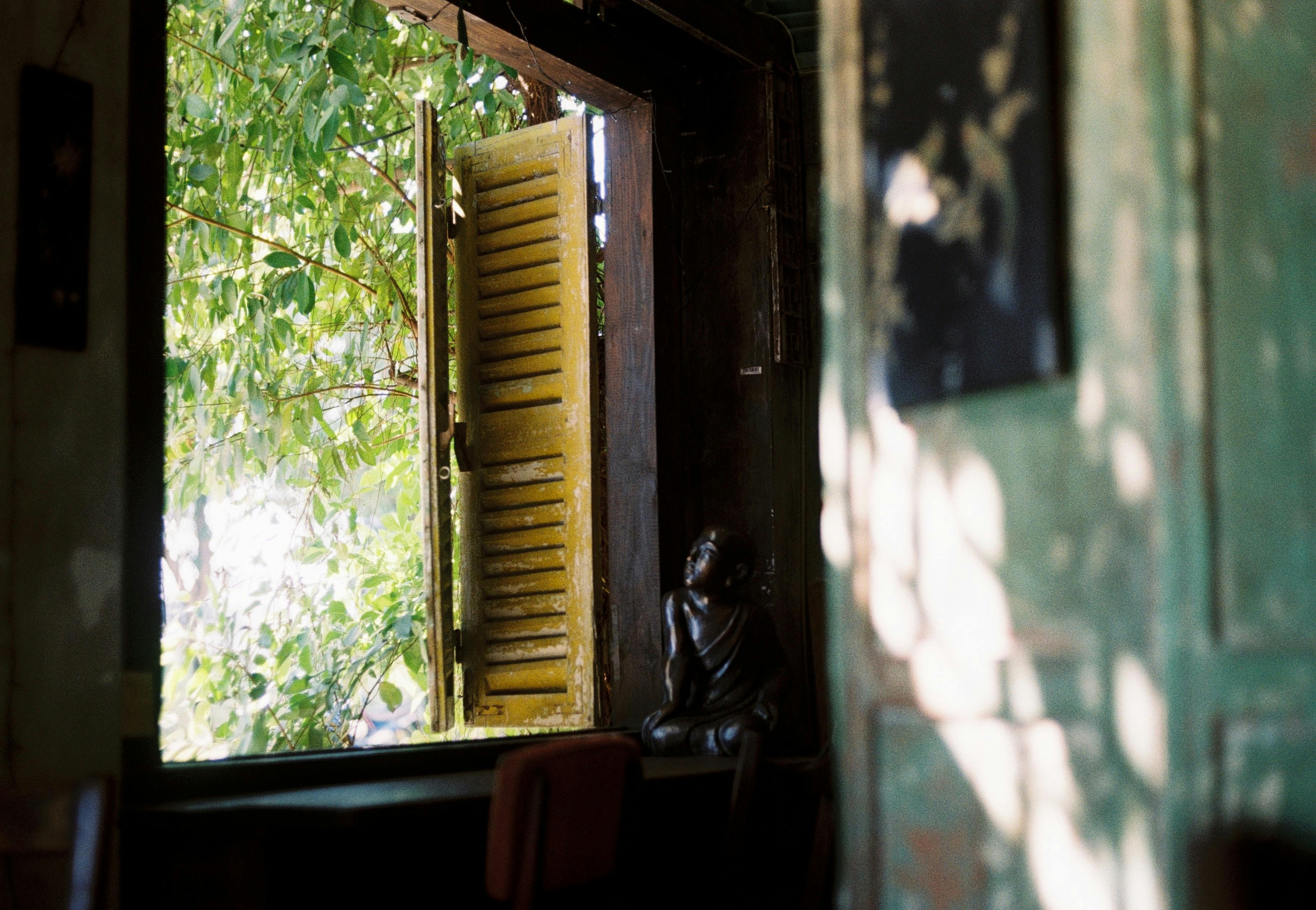 Sunlight filters through an open vintage shuttered window into a rustic room.
