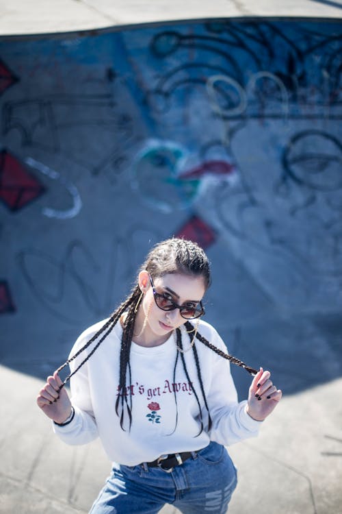 穿著白色長袖襯衫站在裡面的冰坑，同時握住她編織的頭髮的女人的照片