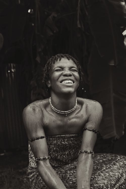 Free Black and white portrait of a smiling young woman with jewelry, enjoying a moment outdoors. Stock Photo