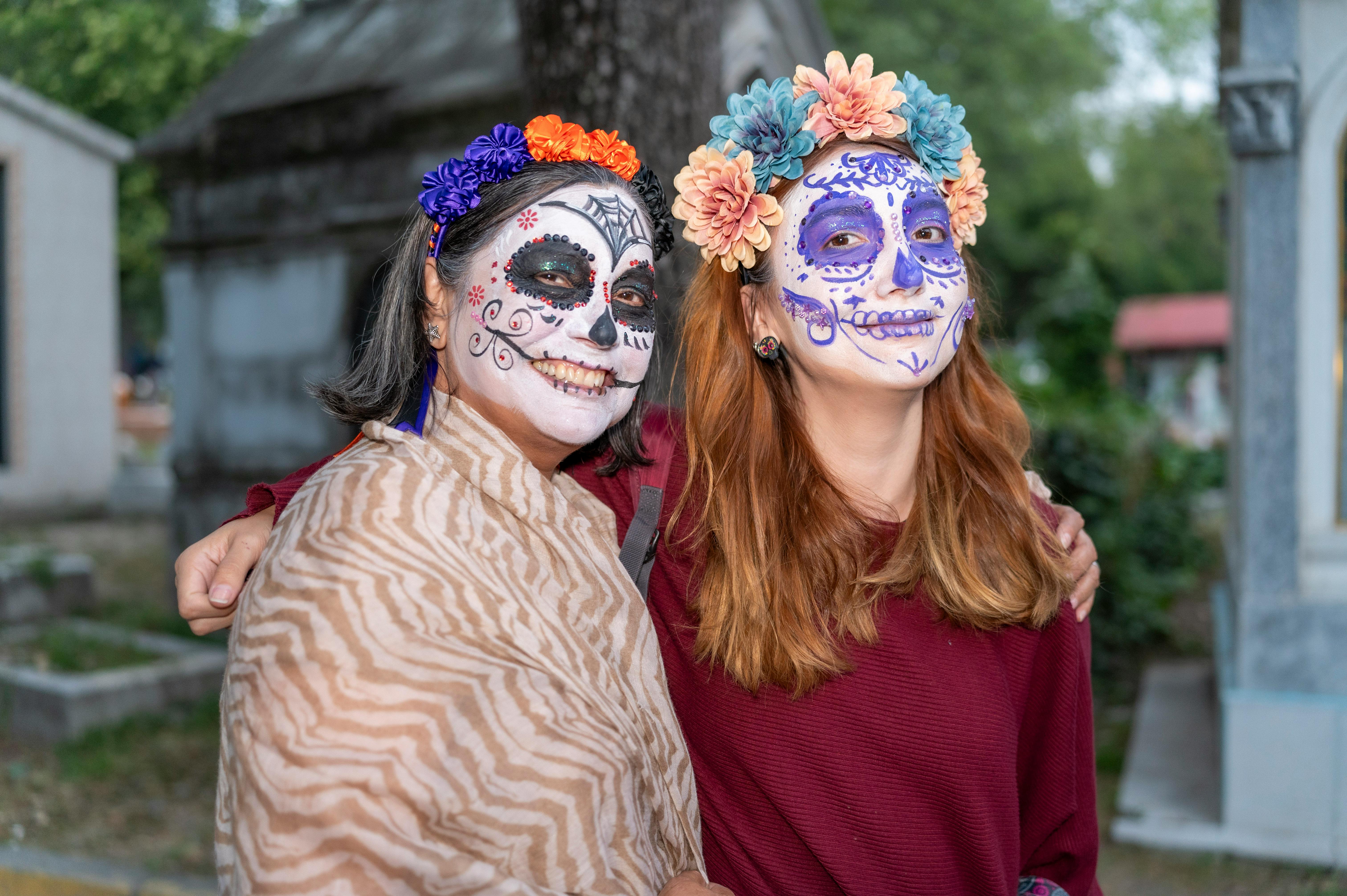 women with painted faces as catrina at cemetery