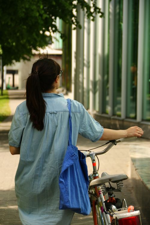 Free Stylish woman walking with a bicycle in Tallinn, Estonia, on a sunny day. Stock Photo