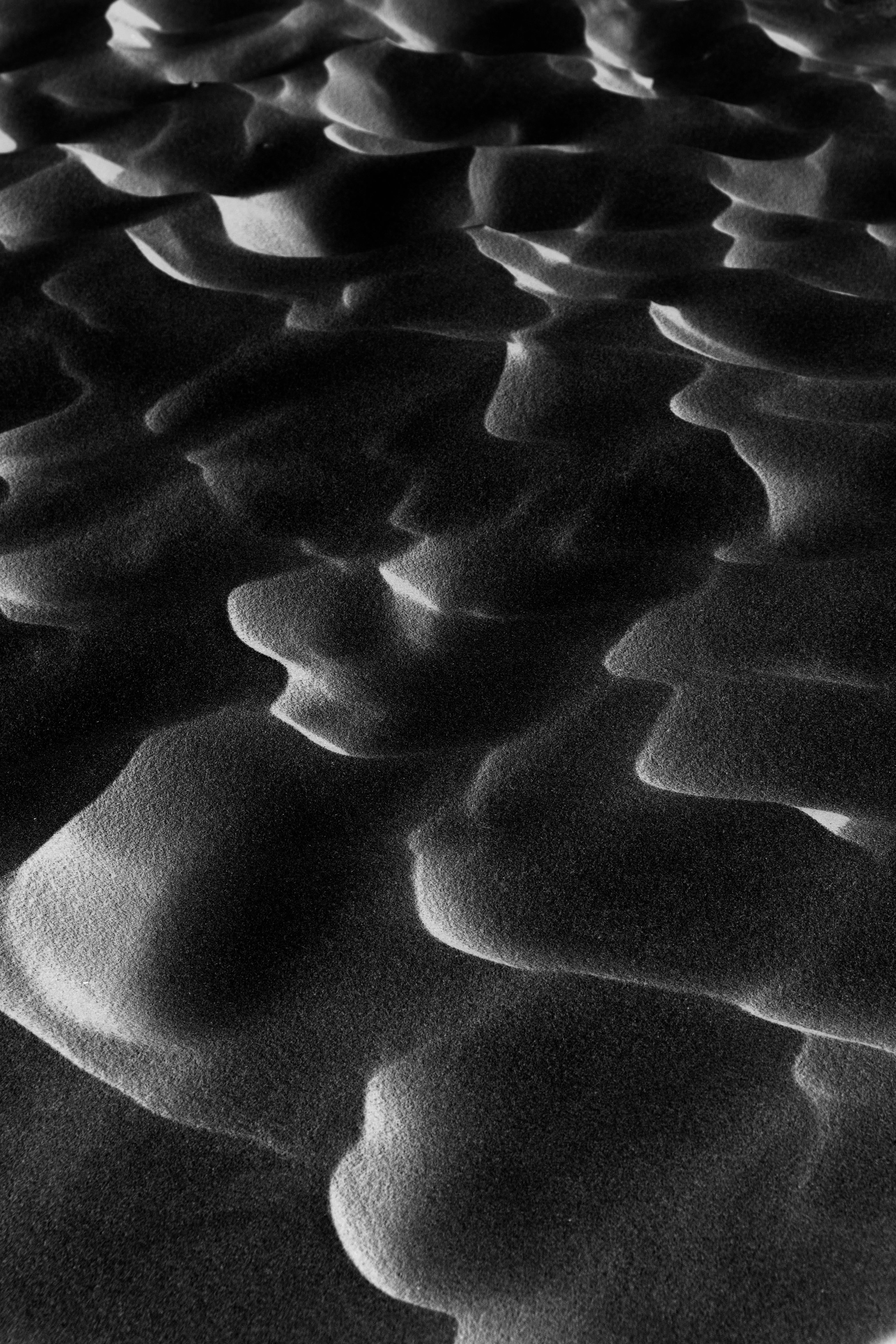 A black and white abstract close-up of wavy sand dunes textures creating an artistic landscape.