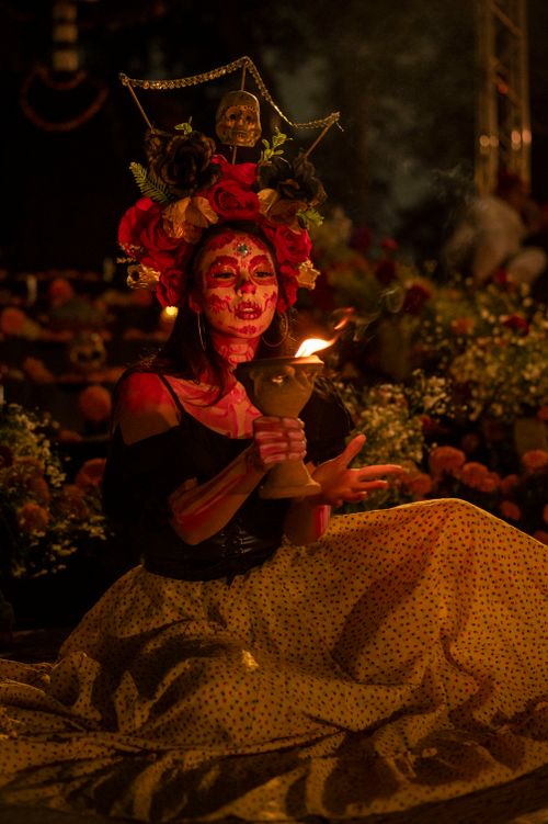 Free Vivid Dia de Muertos scene featuring a woman in traditional attire holding a torch. Stock Photo
