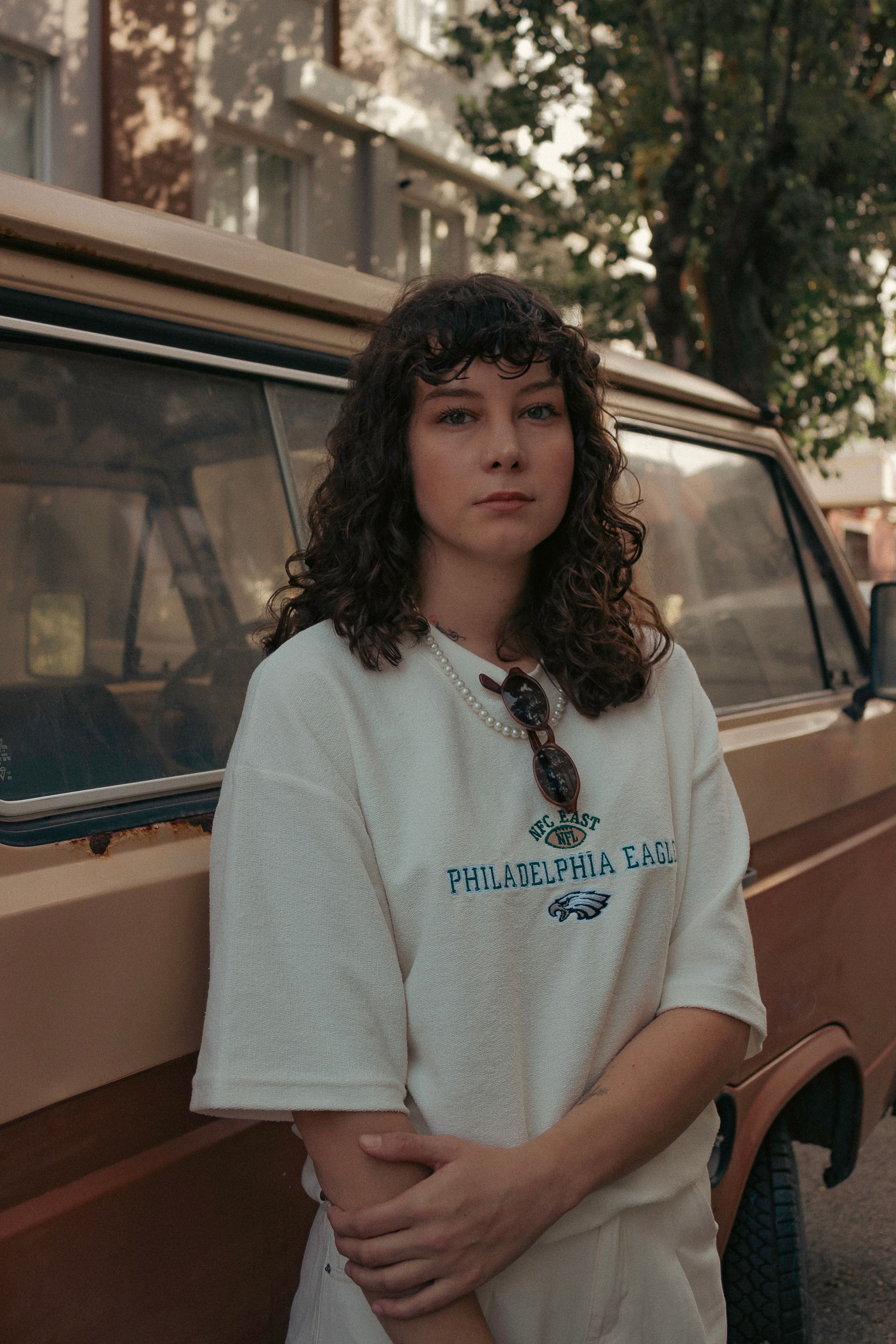 Young woman in casual fashion stands near a vintage van on an Ankara street.