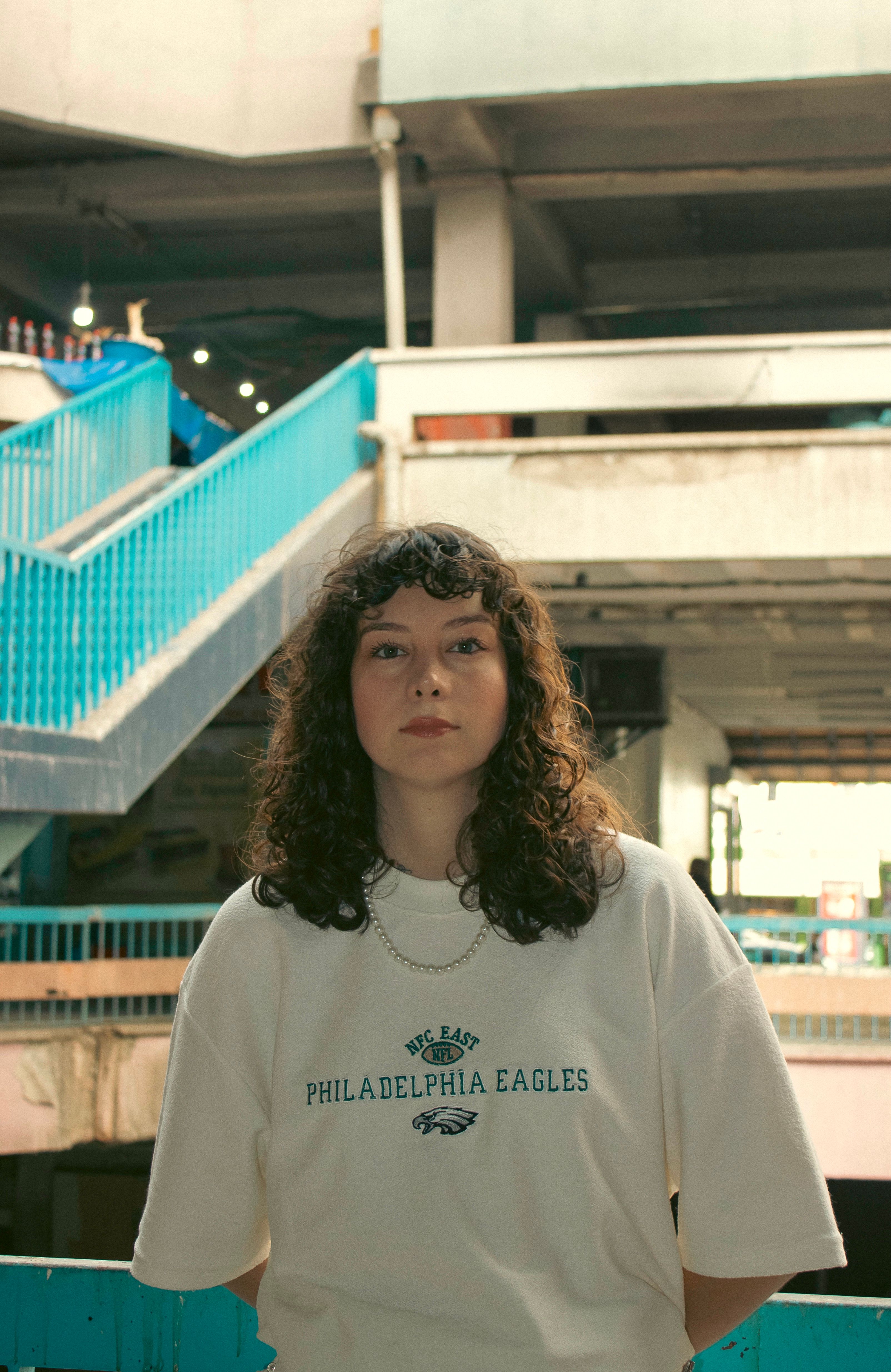 Young woman with curly hair posing in an Ankara parking garage with a relaxed fashion style.