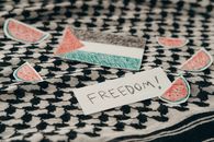 Palestinian flag and freedom note on keffiyeh surrounded by watermelon symbols.