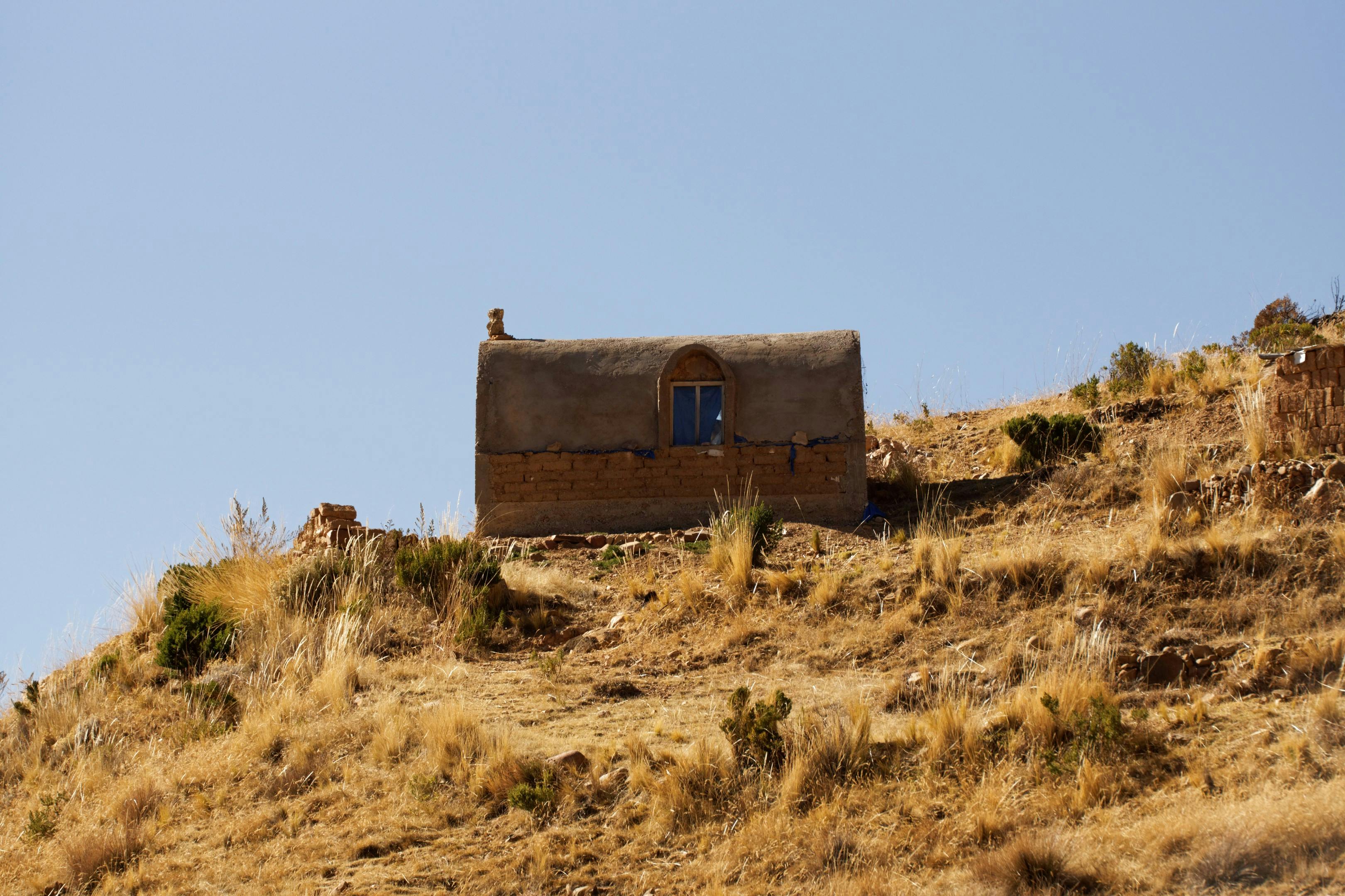 an old house on a hill under blue sky