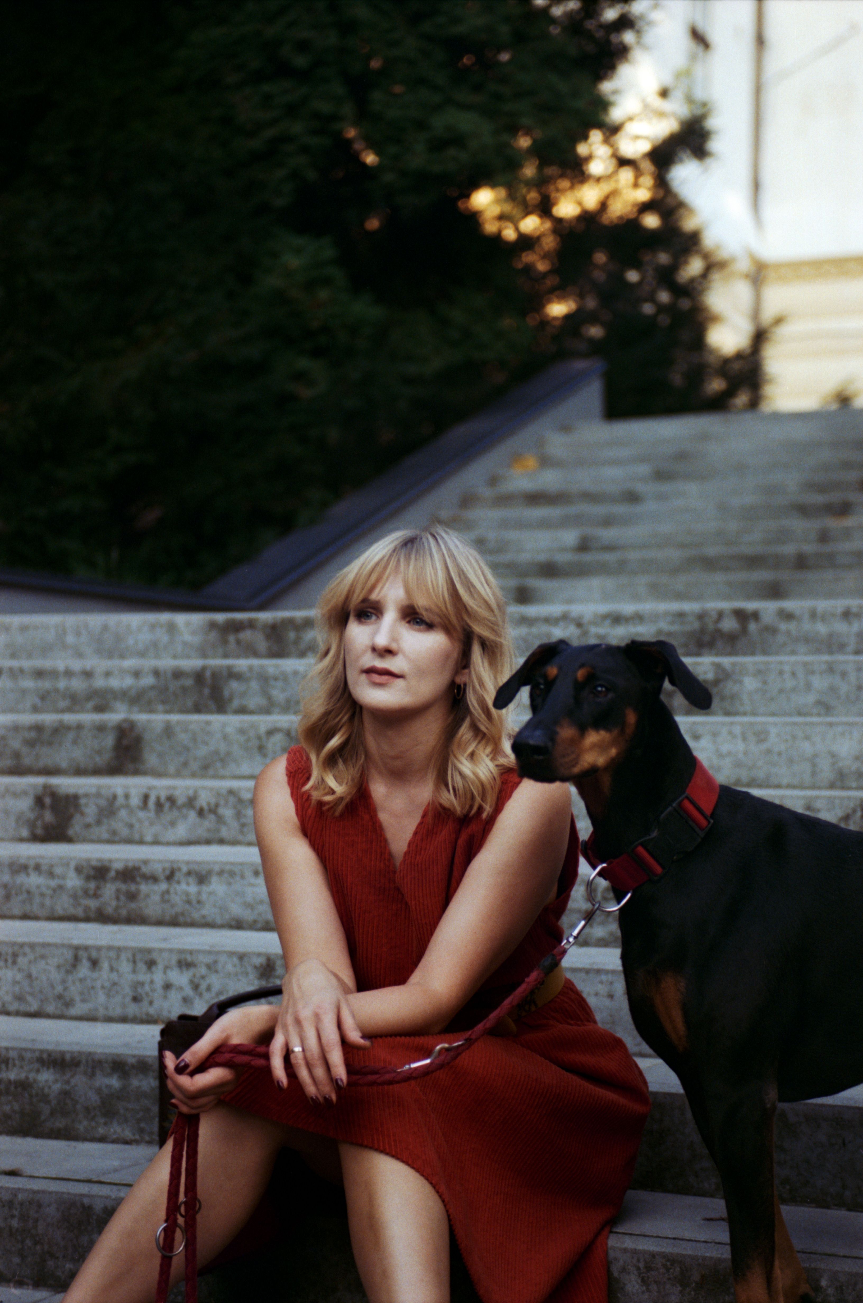 Blonde woman sits with her Doberman on concrete steps in Lviv, Ukraine.