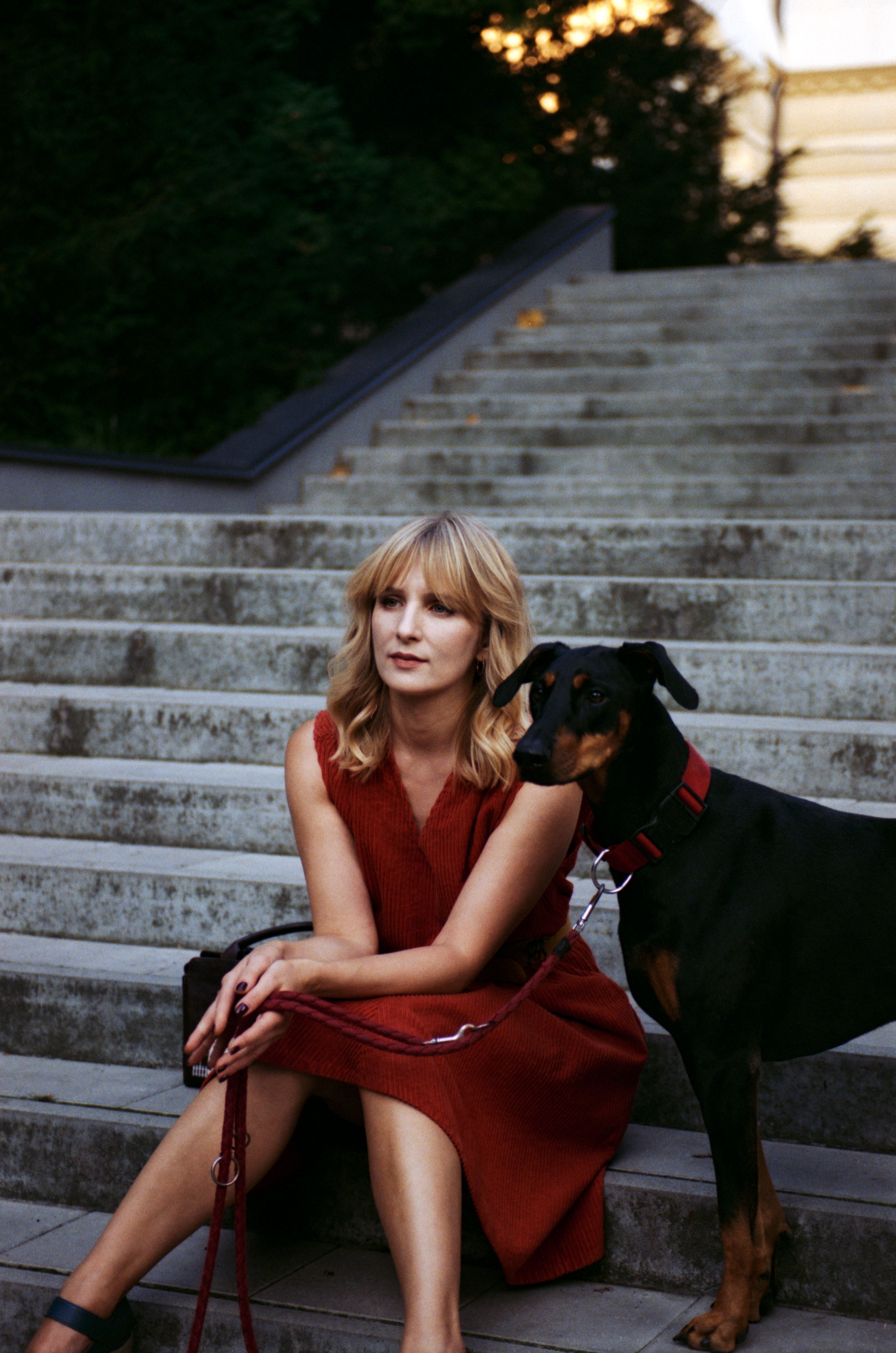 Blonde woman sitting with Doberman on steps in Lviv.