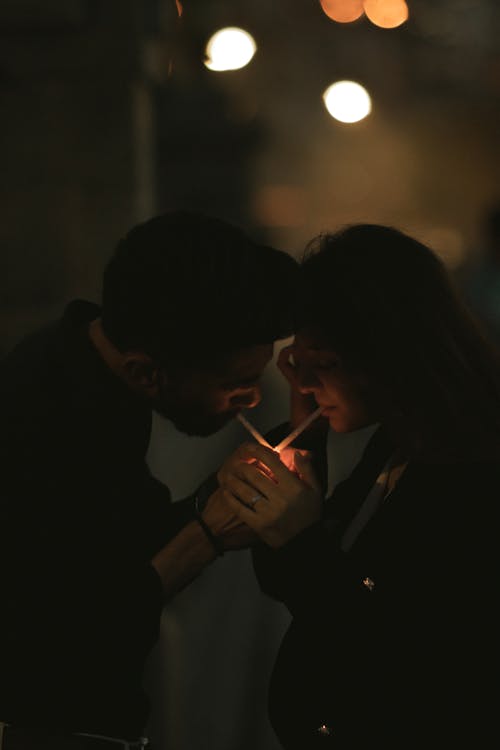Man and Woman Lighting Cigarettes from One Lighter 