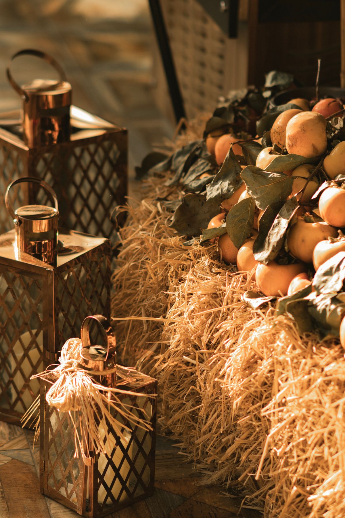 Persimmons and lanterns styled on a hay bale in warm light