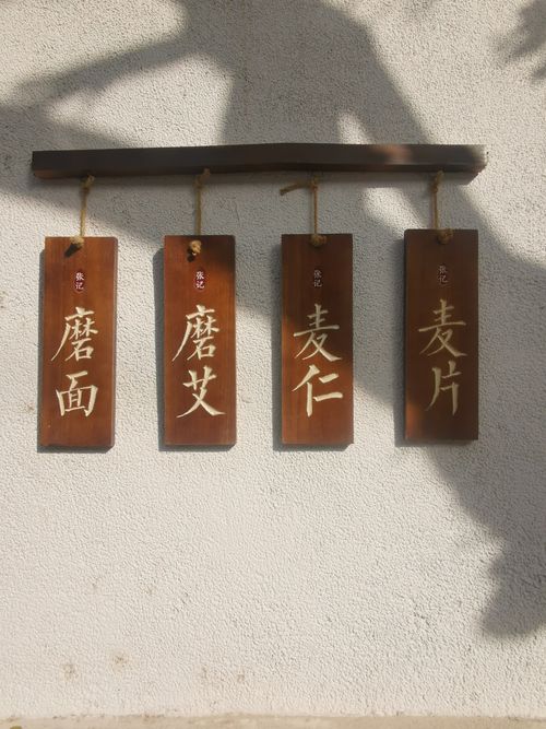 Free Four wooden signs featuring Chinese calligraphy hanging against a textured wall. Stock Photo