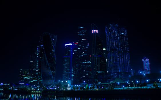 Dramatic view of Moscow's skyline with iconic skyscrapers beautifully illuminated at night.