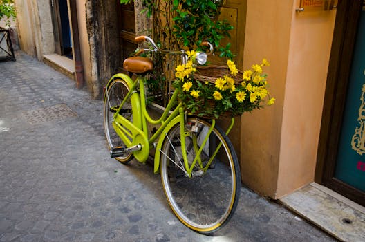 鹅卵石街道上，一辆充满活力的绿色自行车挂着一篮子盛开的黄色花朵