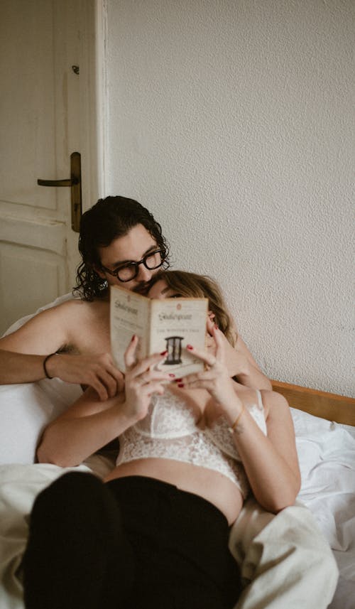 A man and woman reading a book on a bed