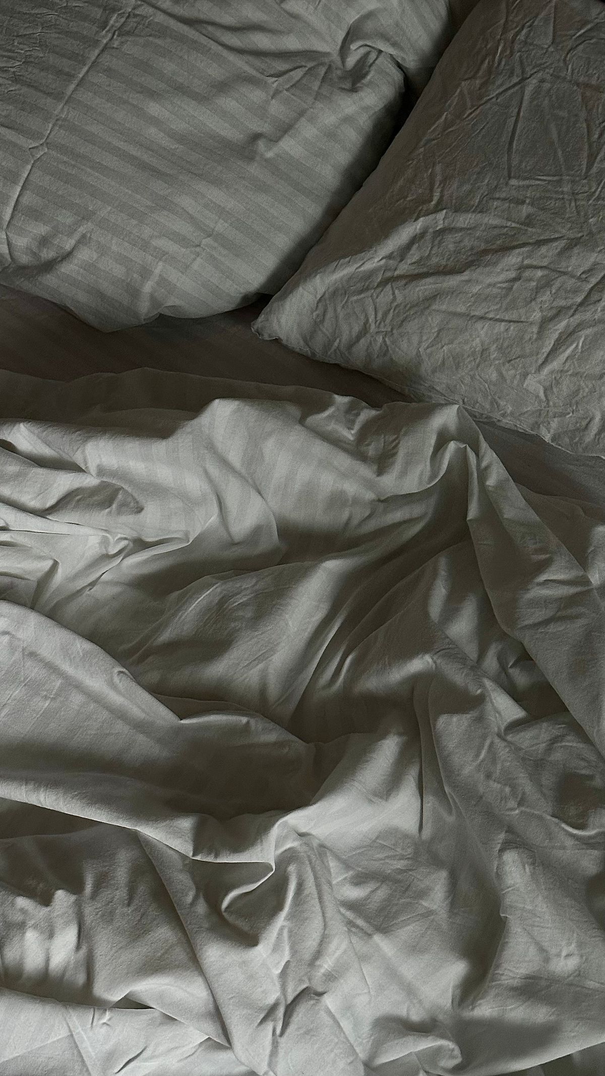 Close-up of naturally wrinkled cotton bed linen showing its weave and folds