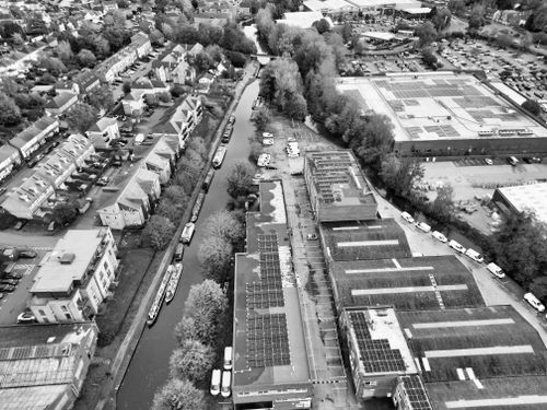 Free Black and white aerial view of a canal and urban landscape in Hertfordshire, England, showcasing buildings and boats. Stock Photo