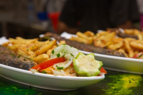 Free Close-up of a delicious meal with grilled fish, fries, and fresh salad on a plate. Stock Photo