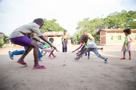 Joyful children play an energetic game in a rural village setting, embracing fun and community.