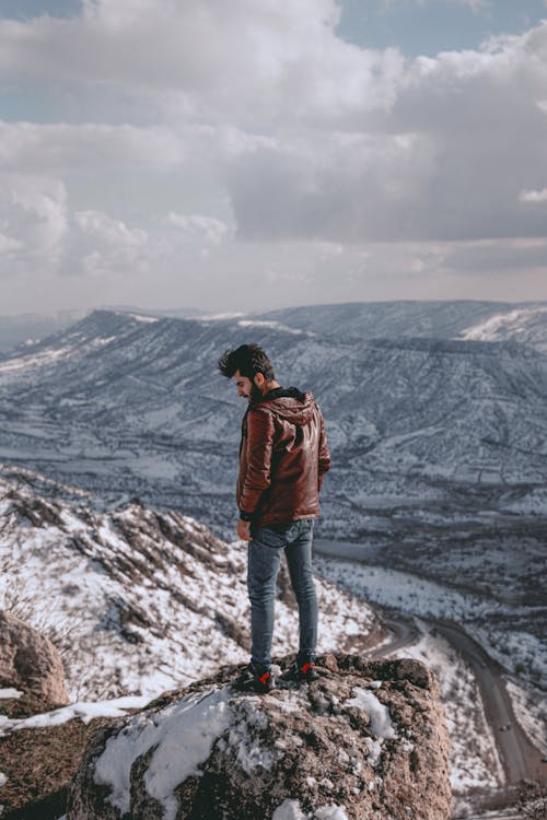 Man Standing on Rock over Valley in Snow