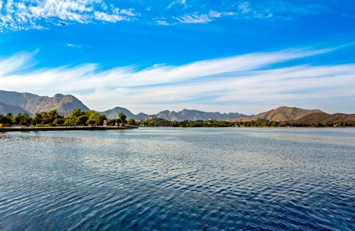 Free Peaceful landscape of a lake with hills under blue skies in Udaipur, India. Stock Photo