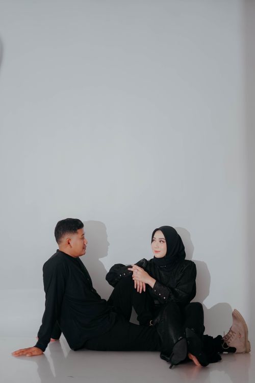 Free A stylish couple sitting on the floor with a white background, focused on fashion and togetherness. Stock Photo