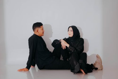 Free Stylish Muslim couple sitting together in modern black outfits, showcasing contemporary fashion. Stock Photo